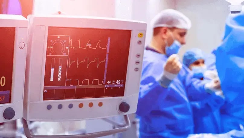 EKG machine with surgeons in the background