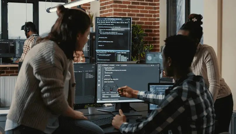 3 people reviewing code on a computer